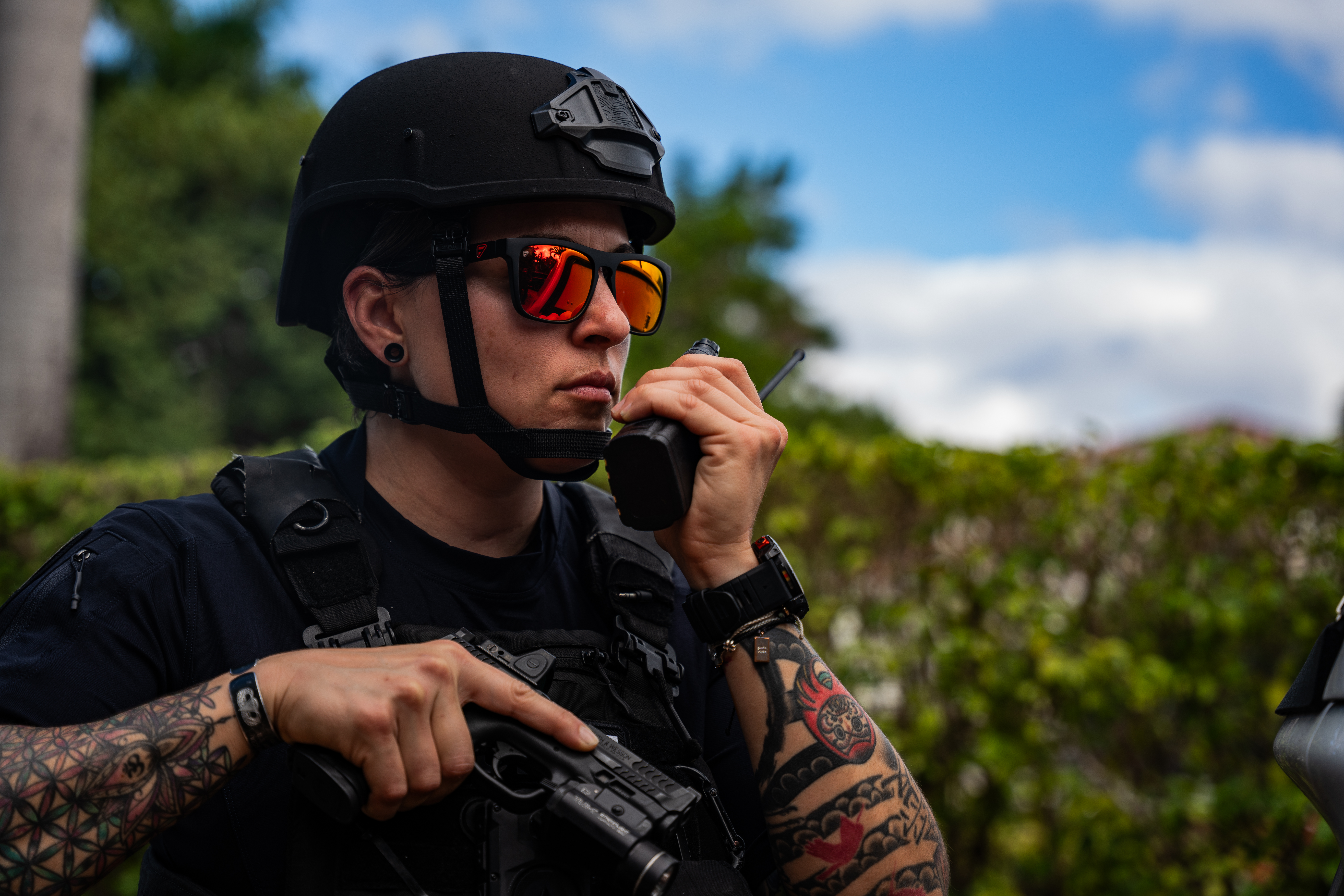 A female police officer wearing an Team Wendy EPIC Responder helmet uses her radio.