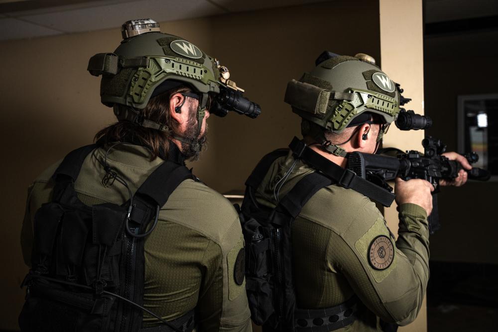 2 law enforcement officers wearing Team Wendy RIFLETECH helmets and other tactical gear clearing a room.