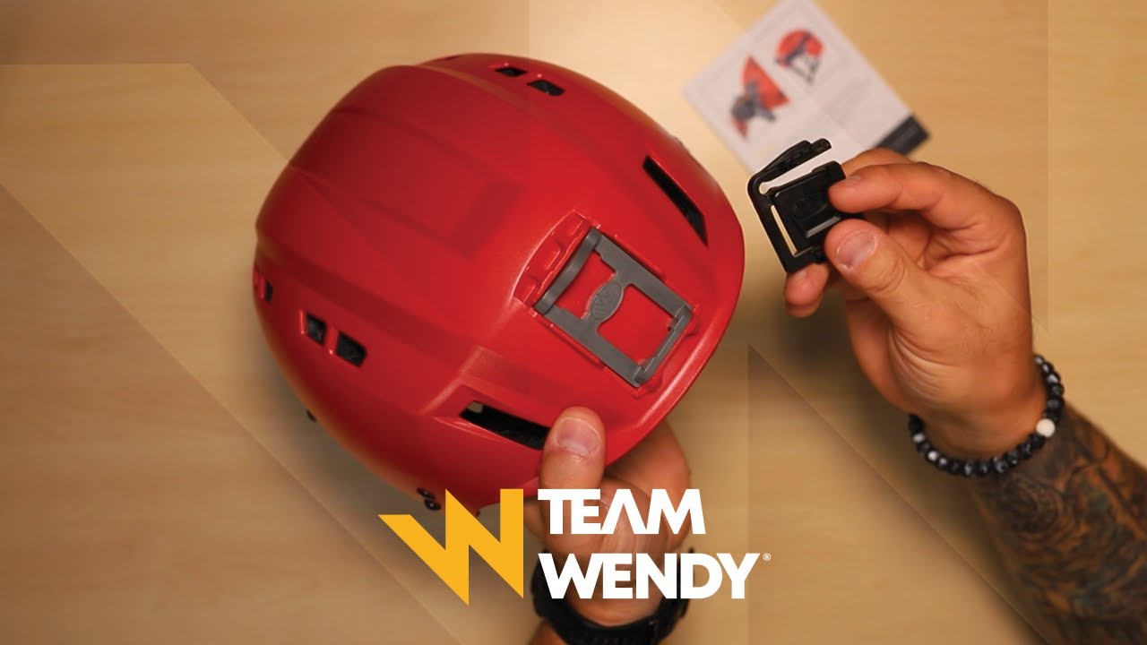 Person installing a shroud headlight adapter to a red Team Wendy SAR Backcountry helmet