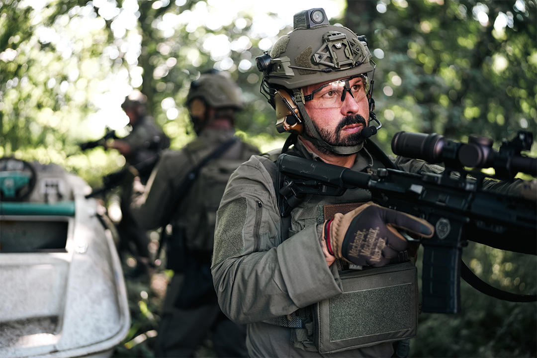 Man in helmet and safety goggles holding a gun